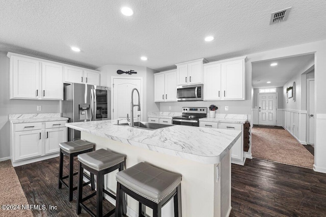 kitchen featuring white cabinetry, stainless steel appliances, sink, and a center island with sink