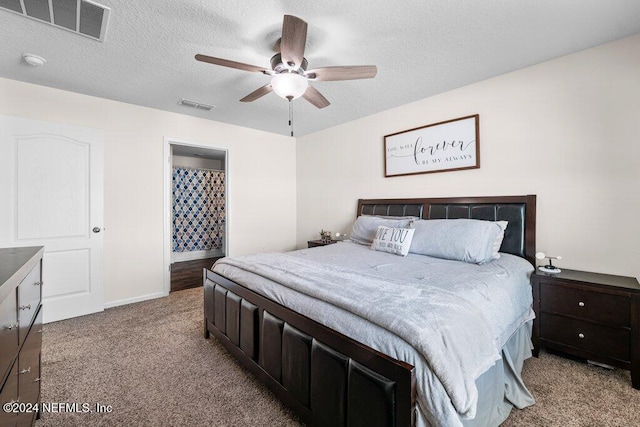 bedroom featuring light carpet, ceiling fan, connected bathroom, and a textured ceiling