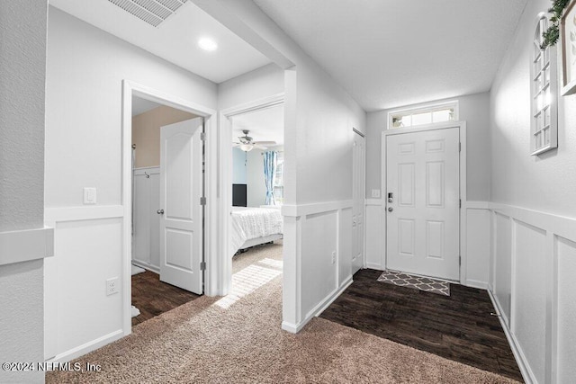 entrance foyer featuring ceiling fan and dark colored carpet