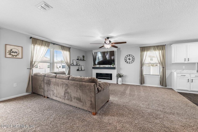 carpeted living room with ceiling fan and a textured ceiling