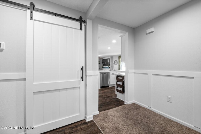 hallway featuring dark wood-type flooring, a barn door, and sink