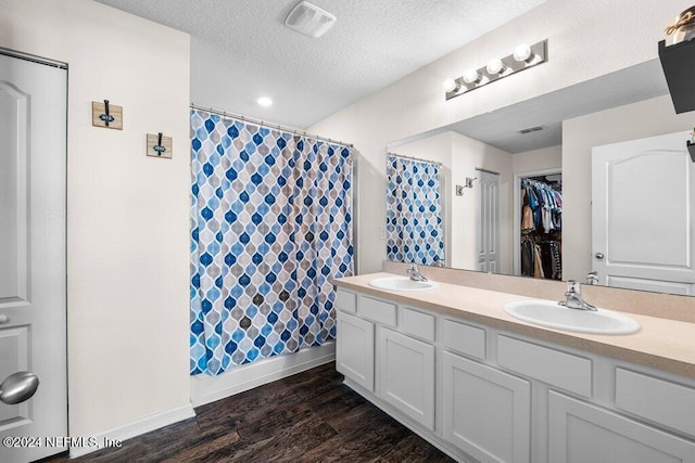 bathroom featuring shower / tub combo with curtain, vanity, hardwood / wood-style floors, and a textured ceiling