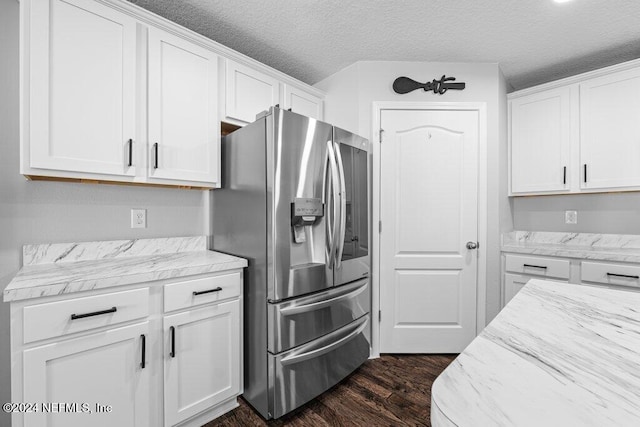 kitchen featuring dark hardwood / wood-style floors, white cabinetry, light stone counters, stainless steel fridge with ice dispenser, and a textured ceiling