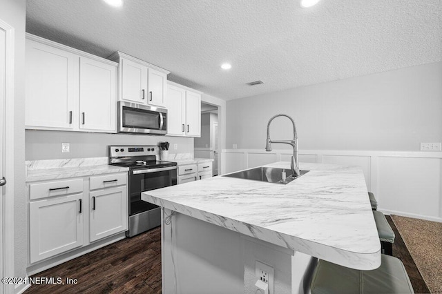 kitchen with white cabinetry, sink, a kitchen island with sink, and appliances with stainless steel finishes