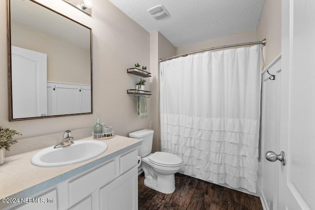 bathroom with hardwood / wood-style floors, vanity, a textured ceiling, toilet, and walk in shower