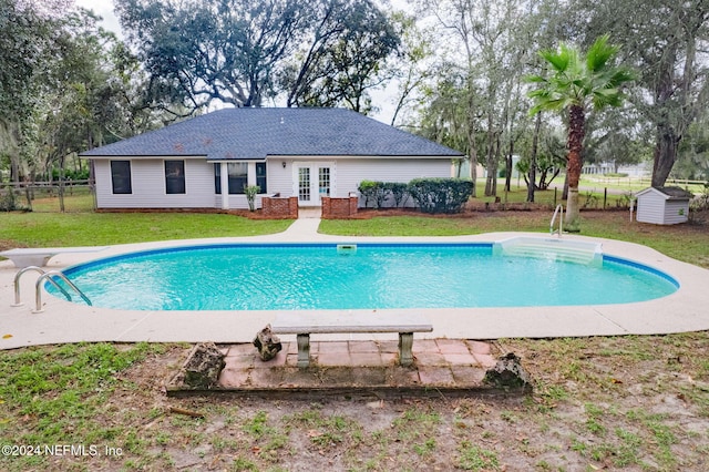 view of pool featuring a diving board, a lawn, and a storage shed