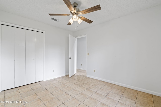 unfurnished bedroom featuring light tile patterned flooring, ceiling fan, a textured ceiling, and a closet