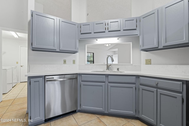 kitchen featuring sink, light tile patterned floors, stainless steel dishwasher, washing machine and clothes dryer, and gray cabinets