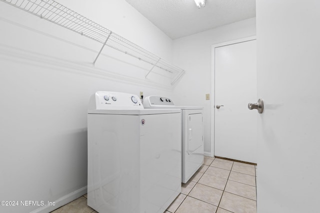 laundry area with washing machine and dryer, a textured ceiling, and light tile patterned flooring