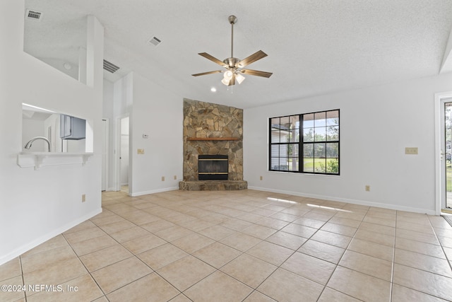 unfurnished living room with a textured ceiling, high vaulted ceiling, ceiling fan, light tile patterned flooring, and a fireplace