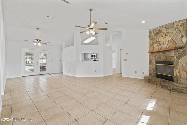 unfurnished living room featuring french doors, a fireplace, light tile patterned floors, high vaulted ceiling, and ceiling fan