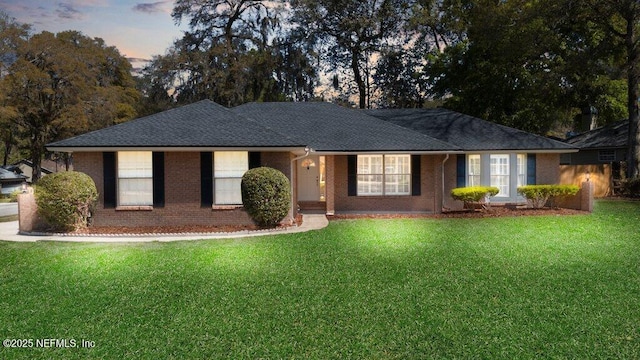 single story home with brick siding, a lawn, and roof with shingles