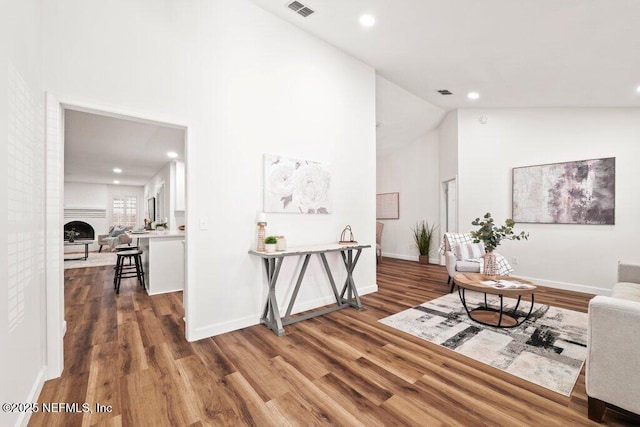 hall with visible vents, high vaulted ceiling, baseboards, and wood finished floors