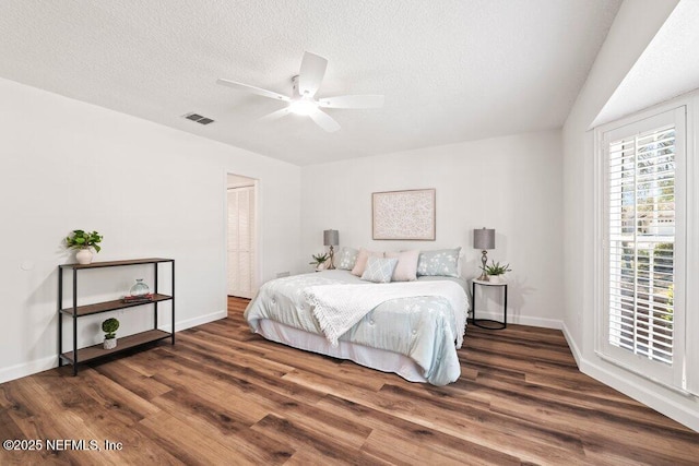 bedroom with visible vents, baseboards, a textured ceiling, and wood finished floors