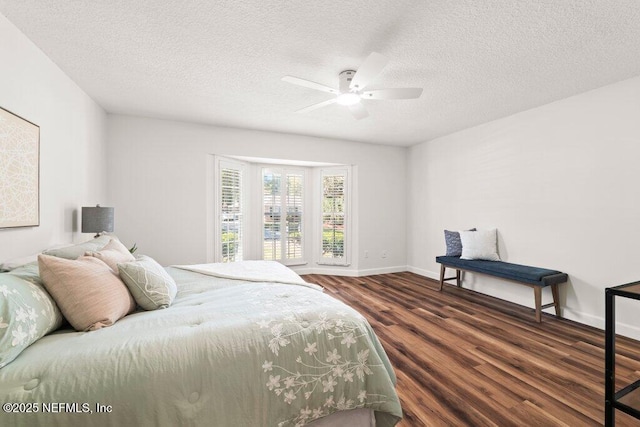 bedroom featuring dark wood-style floors, a textured ceiling, baseboards, and a ceiling fan