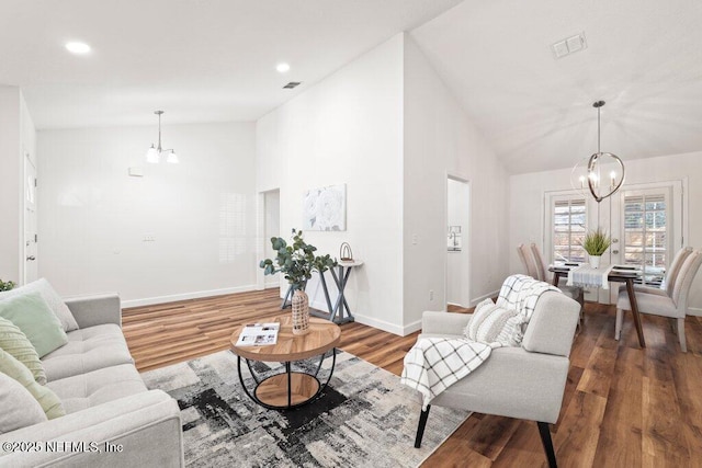 living room featuring a notable chandelier, baseboards, visible vents, and wood finished floors