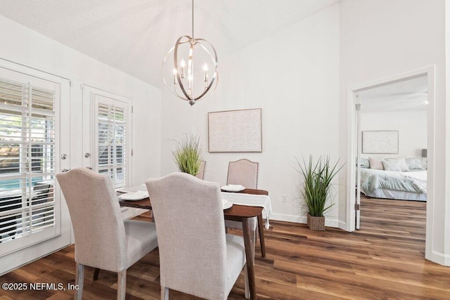 dining area with vaulted ceiling, a notable chandelier, baseboards, and wood finished floors