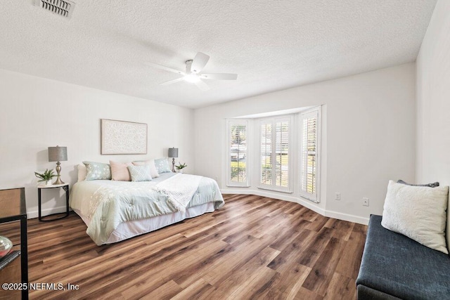 bedroom featuring visible vents, baseboards, a textured ceiling, and wood finished floors