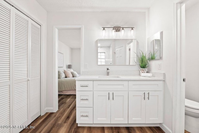 bathroom featuring a closet, toilet, wood finished floors, and vanity