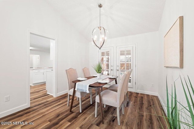 dining space featuring baseboards, lofted ceiling, an inviting chandelier, and wood finished floors