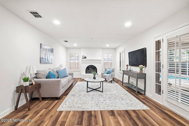 living room featuring dark wood-style floors, visible vents, and a healthy amount of sunlight