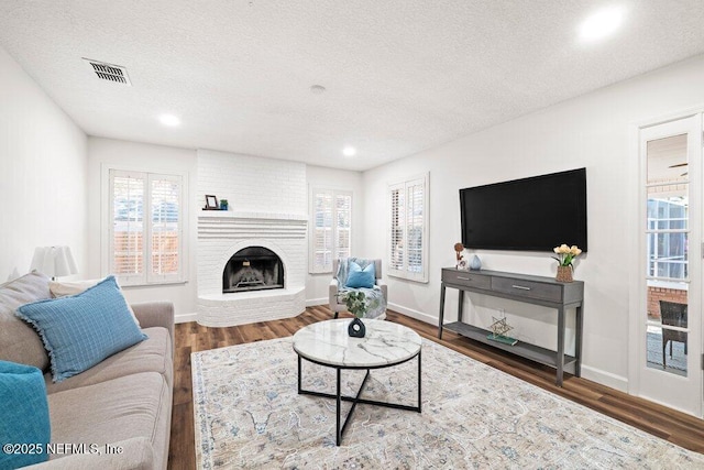 living room with a wealth of natural light, visible vents, and wood finished floors