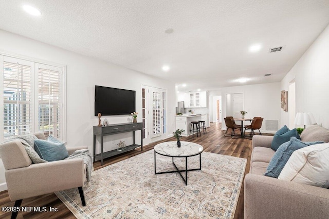 living room featuring recessed lighting, visible vents, dark wood-type flooring, and a textured ceiling