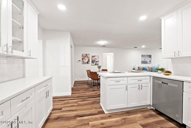 kitchen featuring white cabinets, a peninsula, light wood-style floors, and stainless steel dishwasher