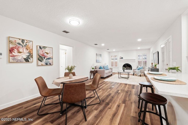 dining room featuring dark wood-style floors, visible vents, a textured ceiling, and baseboards