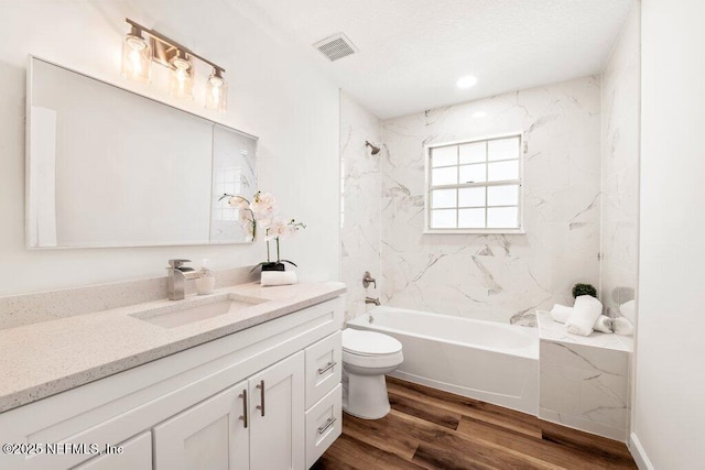 full bath featuring visible vents, toilet, shower / bathing tub combination, wood finished floors, and vanity