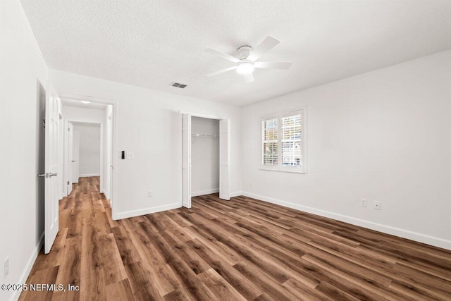 unfurnished bedroom featuring visible vents, a textured ceiling, wood finished floors, a closet, and baseboards