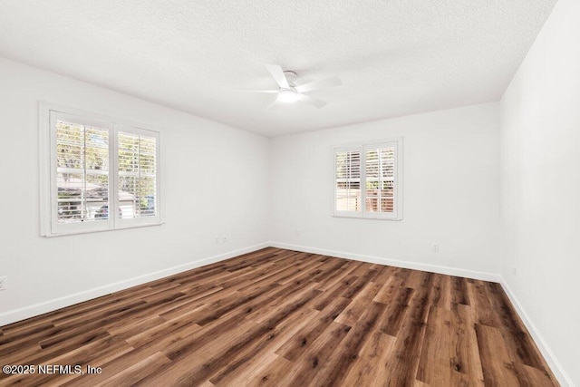 empty room with a wealth of natural light, baseboards, dark wood-style floors, and a ceiling fan