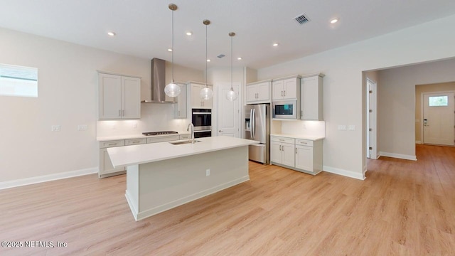 345 Palomar Dr, Saint Johns, FL 32259 - kitchen featuring stainless steel appliances, wall chimney exhaust hood, a center island with sink, light countertops, and light wood-style flooring