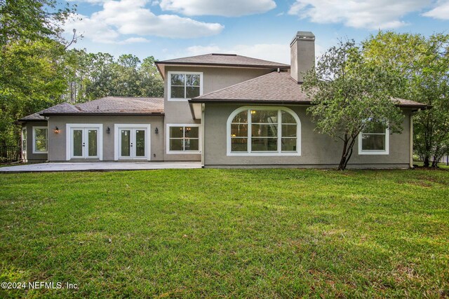 2693 Seneca Dr, Saint Johns, FL 32259 - back of house with french doors, stucco siding, a chimney, a lawn, and a patio area