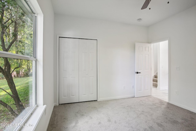 unfurnished bedroom featuring a closet, multiple windows, carpet floors, and ceiling fan