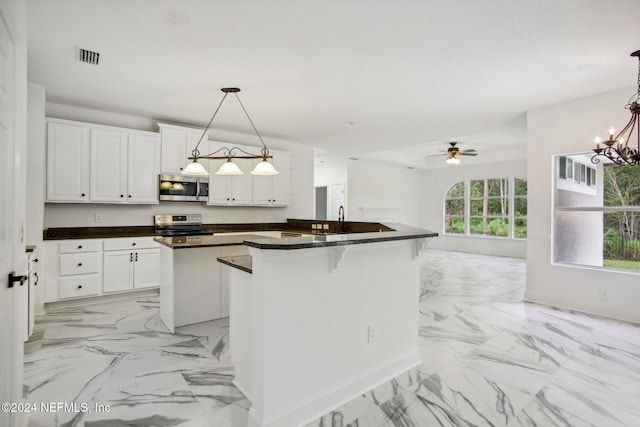 kitchen featuring a kitchen island, a kitchen breakfast bar, white cabinetry, stainless steel appliances, and decorative light fixtures