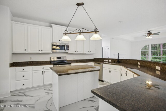 2693 Seneca Dr, Saint Johns, FL 32259 - kitchen with appliances with stainless steel finishes, a sink, white cabinets, and a center island