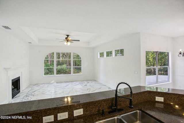 2693 Seneca Dr, Saint Johns, FL 32259 - kitchen with a sink, a raised ceiling, a ceiling fan, open floor plan, and a glass covered fireplace