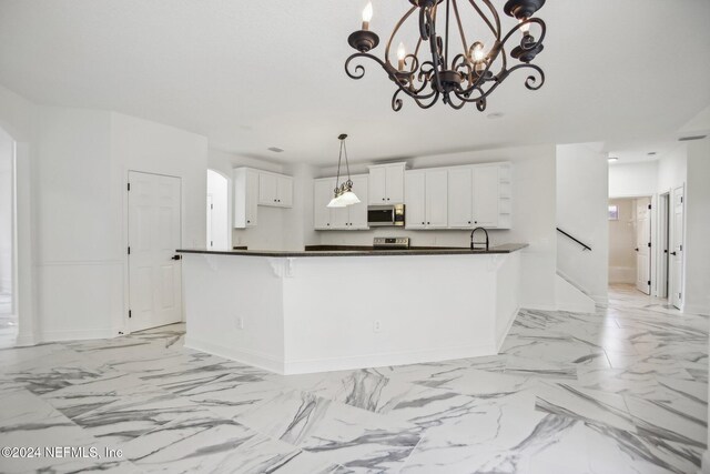 kitchen featuring hanging light fixtures, stainless steel appliances, kitchen peninsula, an inviting chandelier, and white cabinets