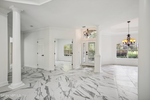 entrance foyer featuring a notable chandelier, ornamental molding, and decorative columns