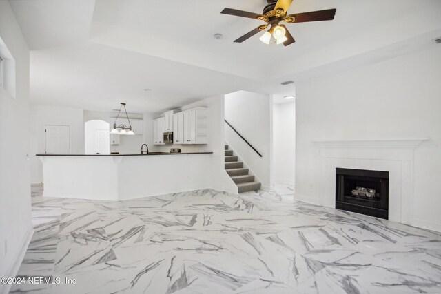 2693 Seneca Dr, Saint Johns, FL 32259 - unfurnished living room with a tray ceiling, a ceiling fan, stairs, a fireplace, and a sink