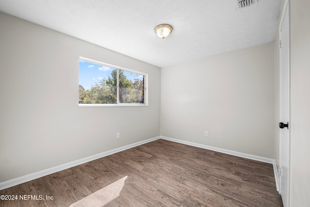 unfurnished room with a textured ceiling and hardwood / wood-style flooring