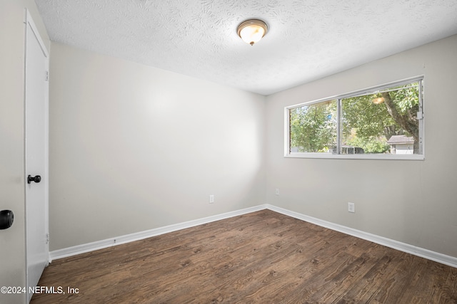 unfurnished room with a textured ceiling and dark hardwood / wood-style flooring