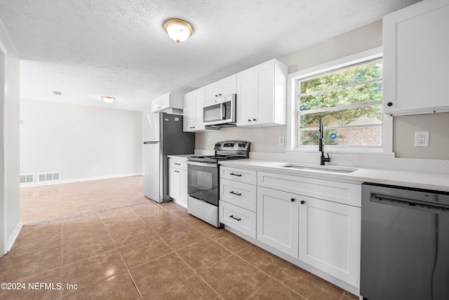 kitchen featuring tile patterned flooring, sink, white cabinetry, appliances with stainless steel finishes, and a textured ceiling