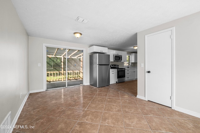 kitchen with light tile patterned floors, white cabinetry, a textured ceiling, sink, and stainless steel appliances