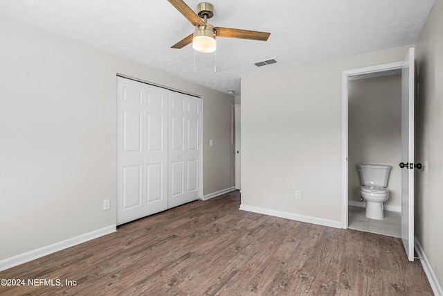 unfurnished bedroom featuring wood-type flooring, a textured ceiling, a closet, ceiling fan, and connected bathroom