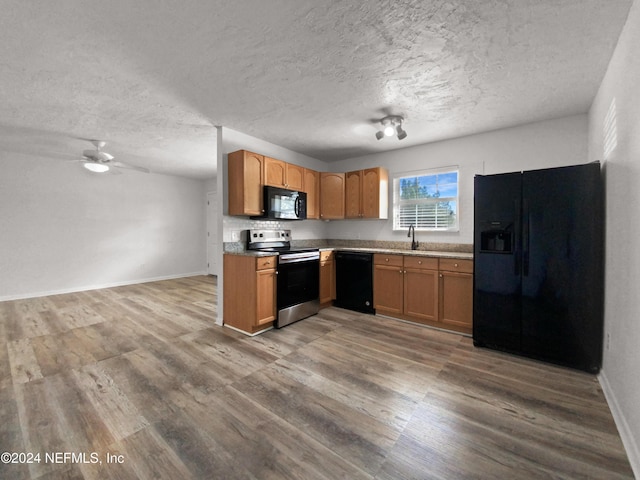 kitchen with black appliances, a textured ceiling, a ceiling fan, wood finished floors, and baseboards