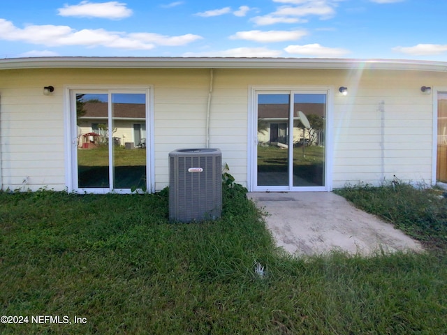 back of house with central air condition unit, a yard, and a patio