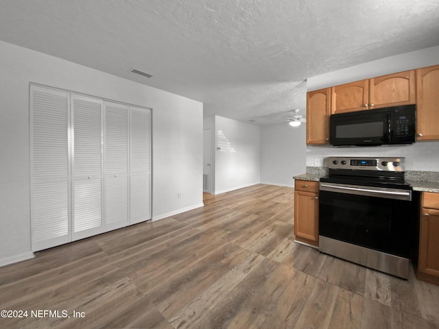 kitchen with stainless steel electric stove, black microwave, baseboards, a textured ceiling, and wood finished floors