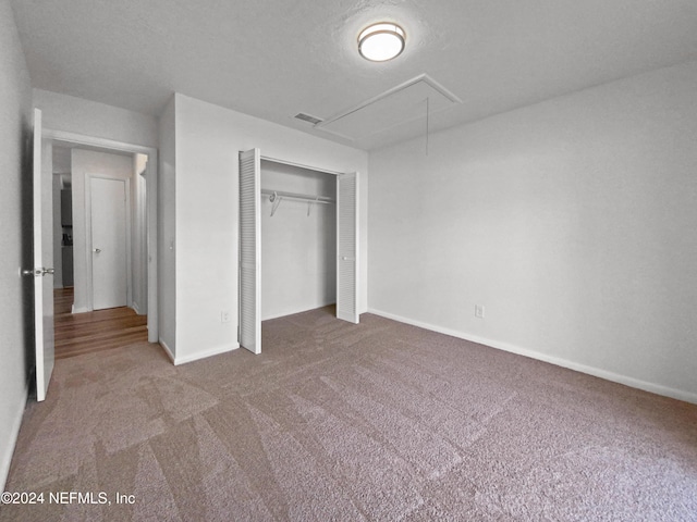 unfurnished bedroom with attic access, carpet flooring, baseboards, and a closet